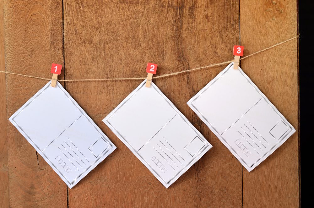 Three blank postcards hanging from numbered pegs