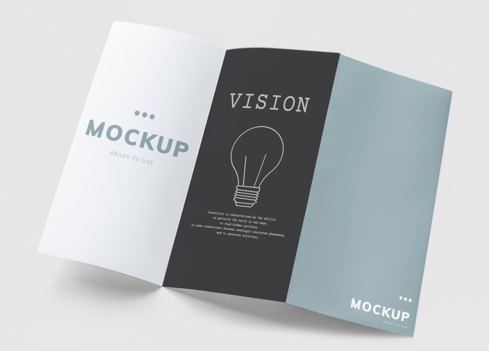 A mockup of an open tri-fold brochure showing three panels in white, black, and light blue with placeholder text and a lightbulb graphic.
